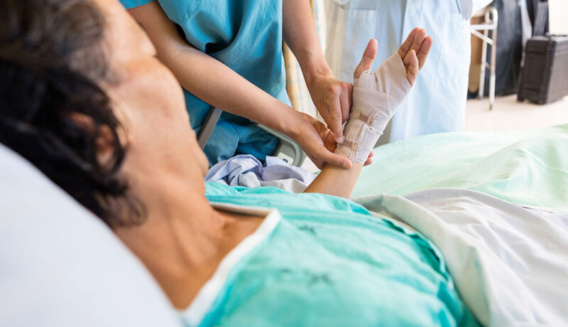 Closeup Of A Nurse Adjusting The Bandage On A Senior Woman's Hand Non-Healing Wounds In Elderly